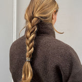 Woman with a braided hairstyle featuring the mixed metal hair cuff, wearing a brown coat against a neutral background