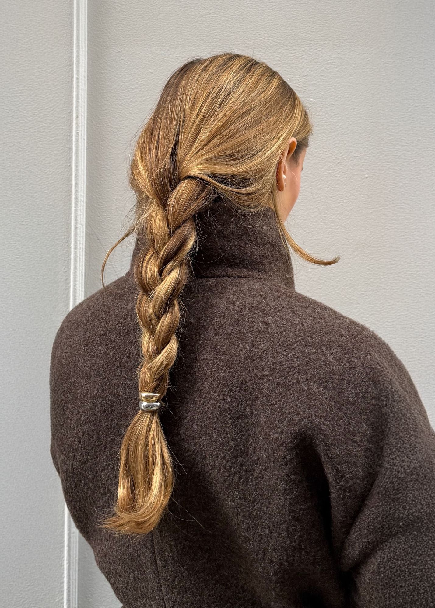 Woman with a braided hairstyle featuring the mixed metal hair cuff, wearing a brown coat against a neutral background