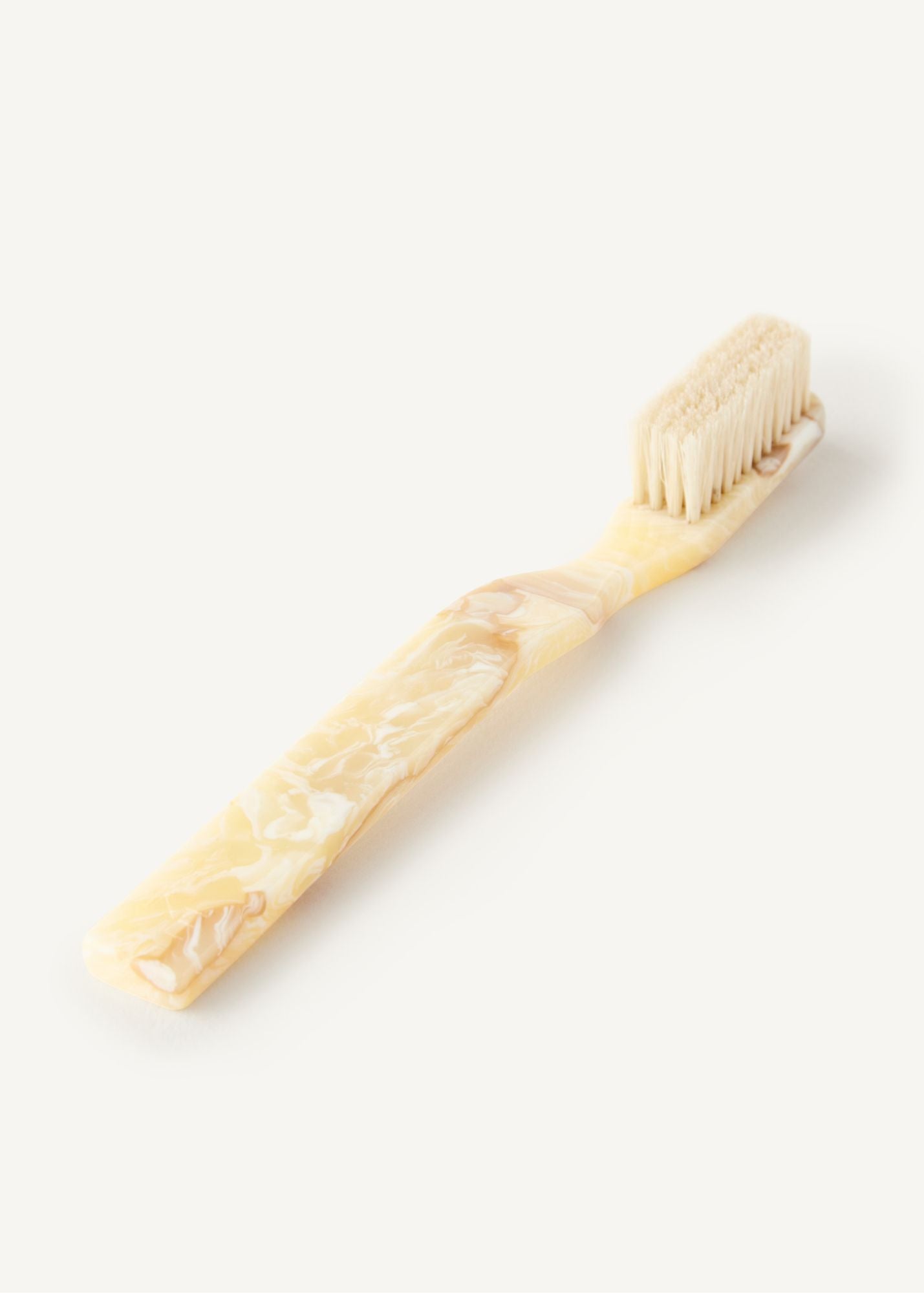 The Detail Brush in Oak, a boar bristle brush in a light cream colour laying flat on white background