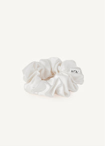 White silk scrunchie on a light beige background