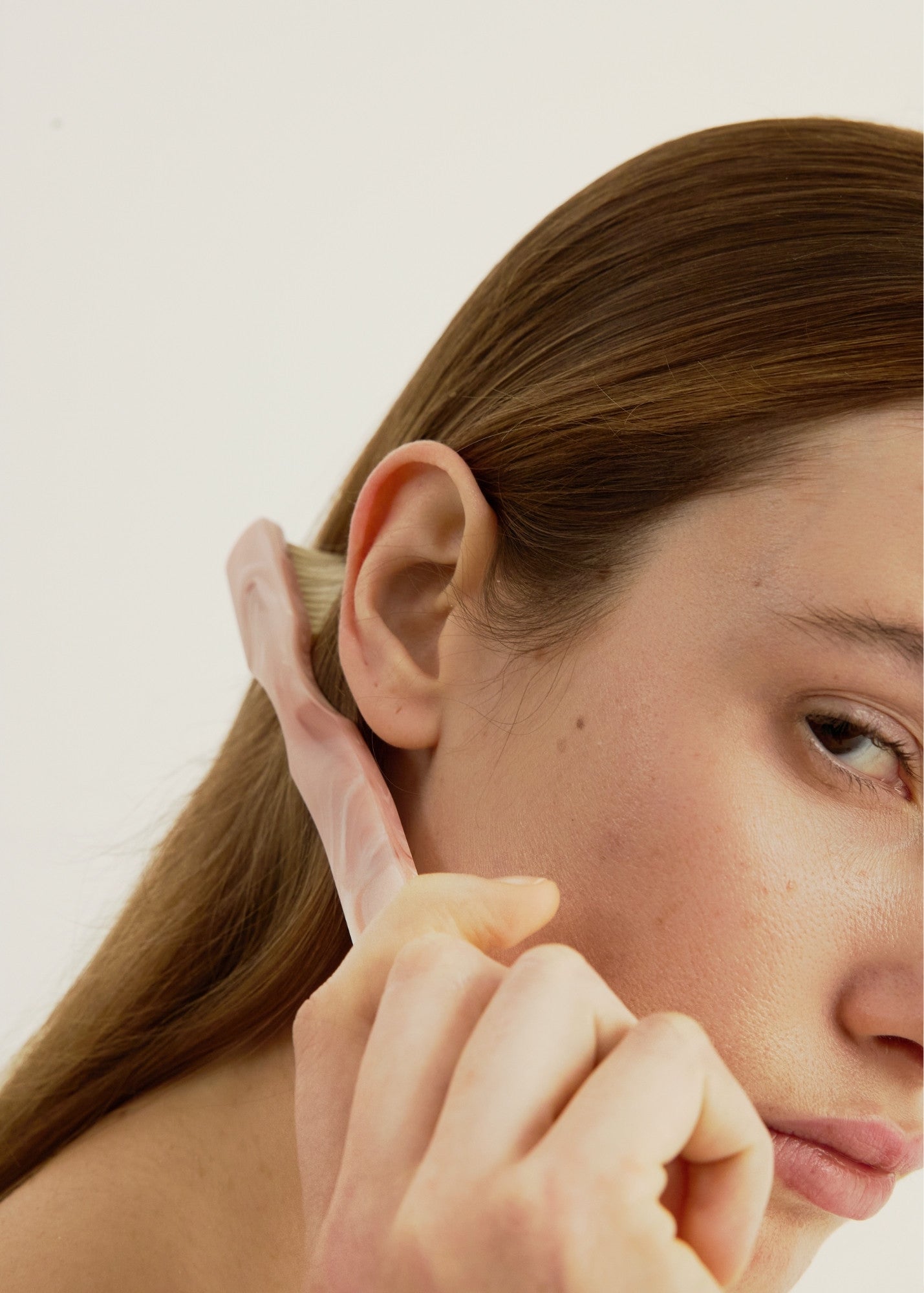 Close-up of a person brushing their hair with a pink coloured hairbrush