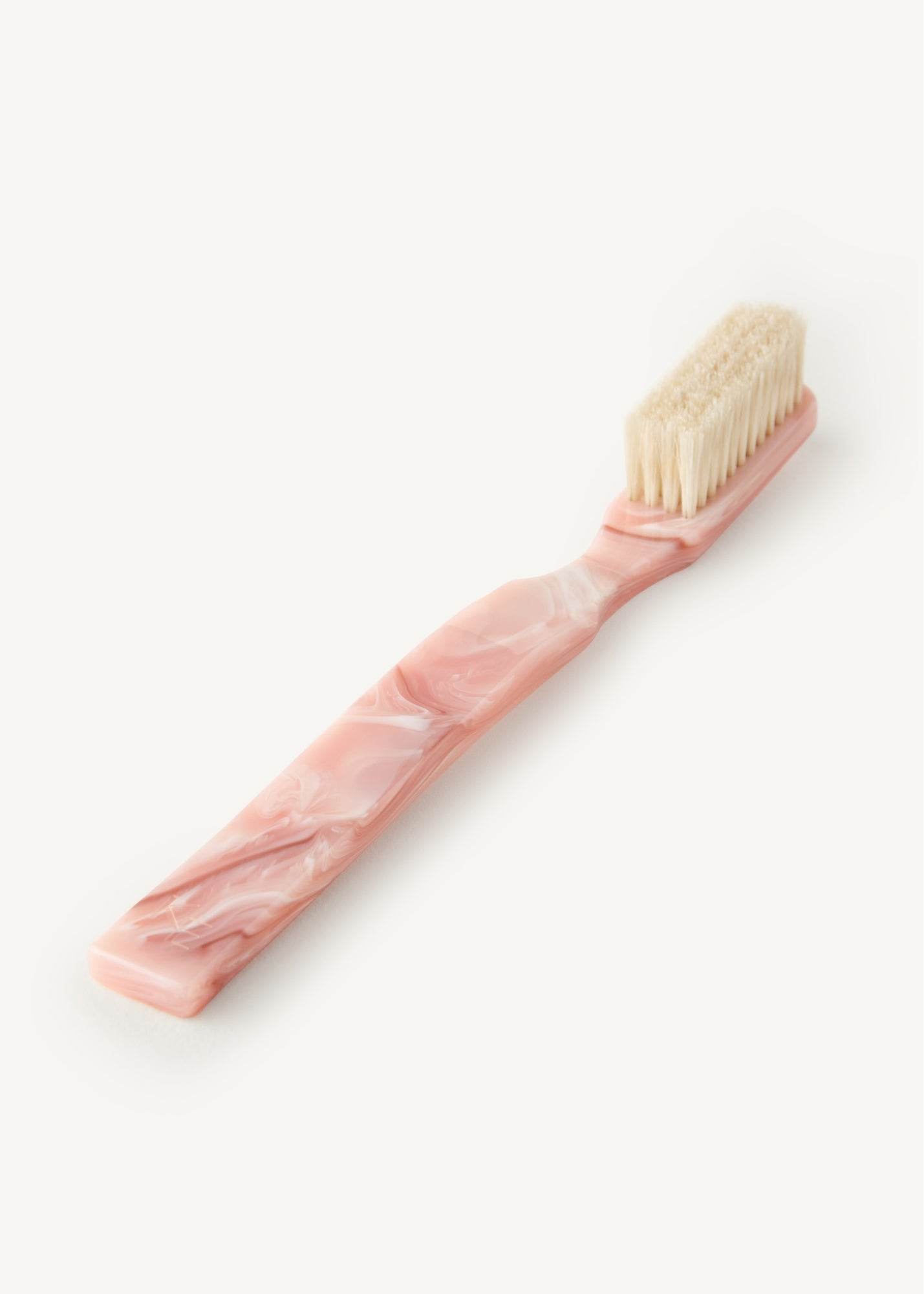 Pink hairbrush with beige coloured bristles on a white background