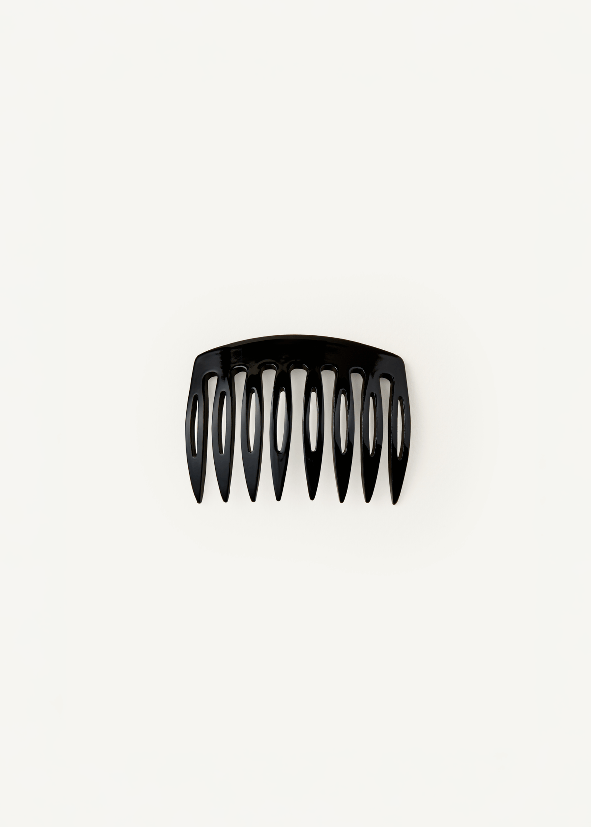 A small, slightly curved comb in black against a neutral background