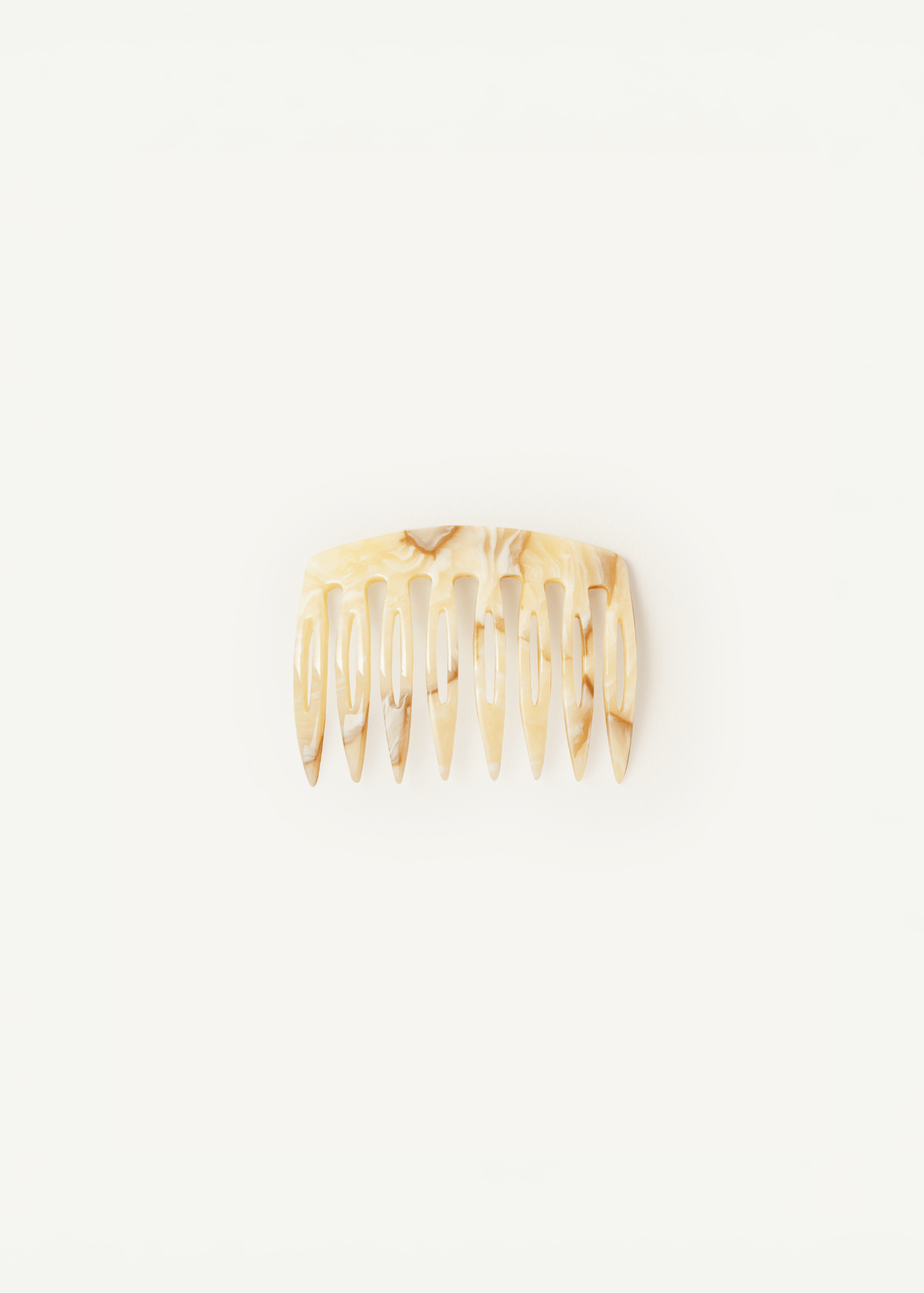 A small, slightly curved comb in a light neutral pattern against a neutral background