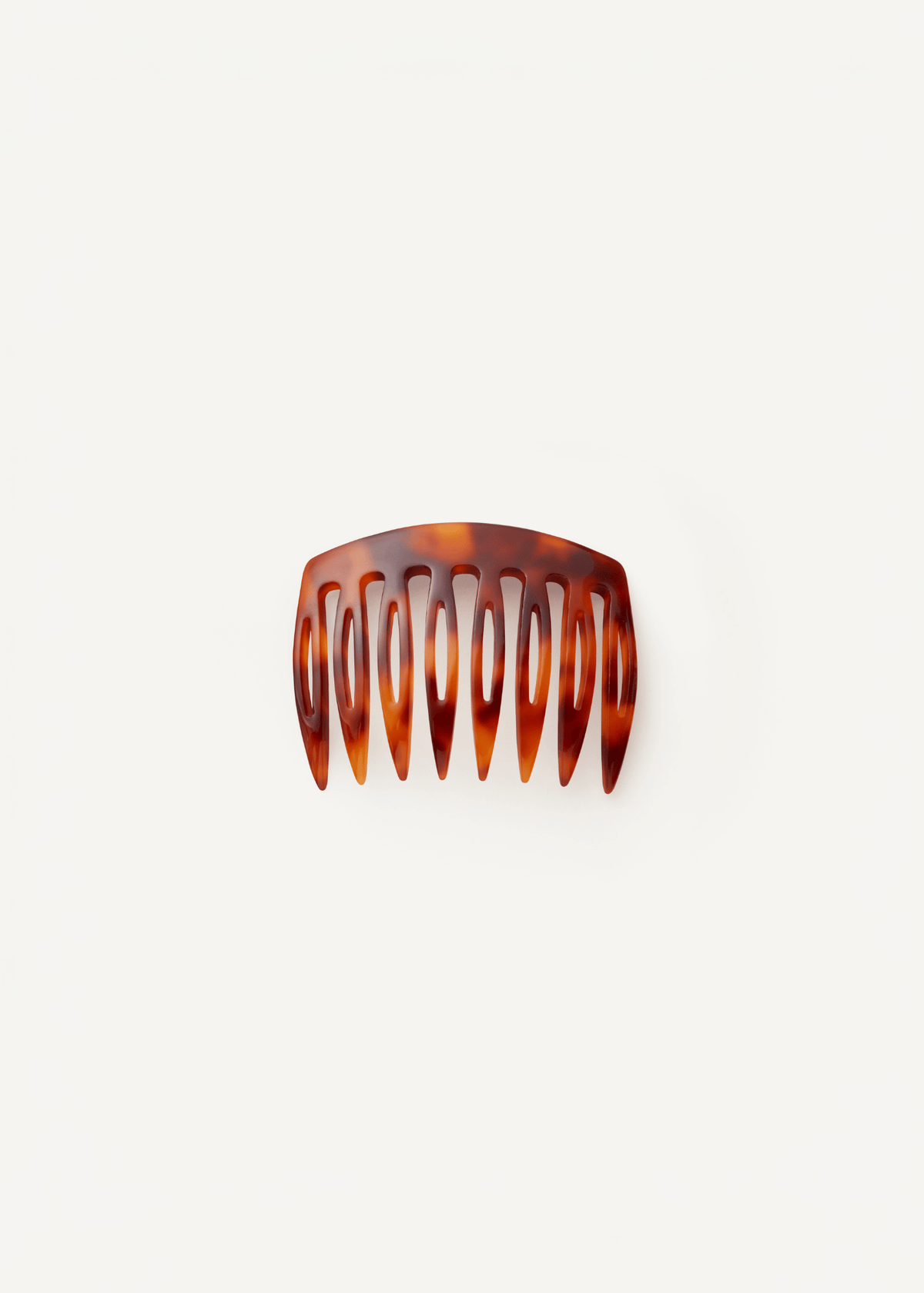 A small, slightly curved comb in a tortoiseshell pattern against a neutral background