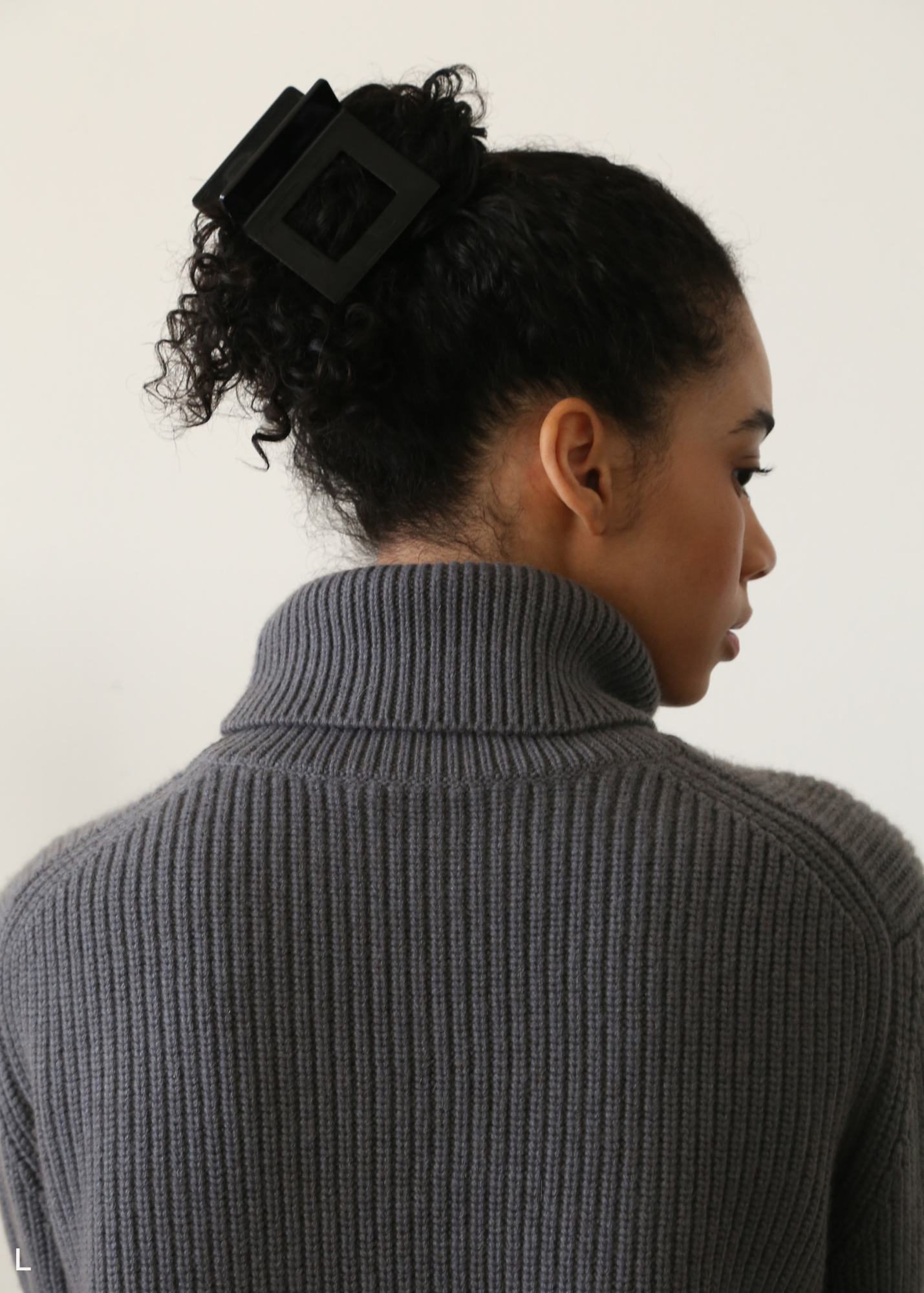 Woman wearing a black hair clip with a plain background.