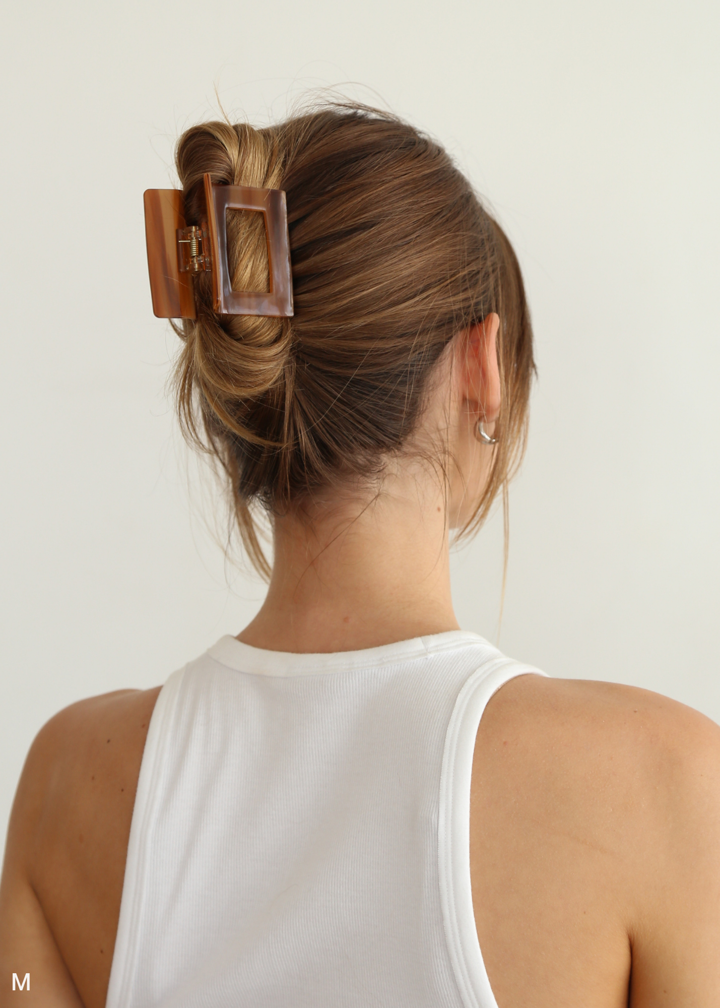 Person with a caramel coloured hair clip in their hair against a white background
