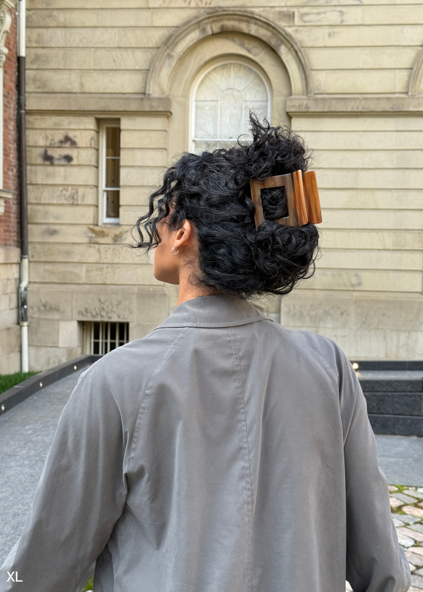 Person with large curly hair wearing an extra large hair clip.