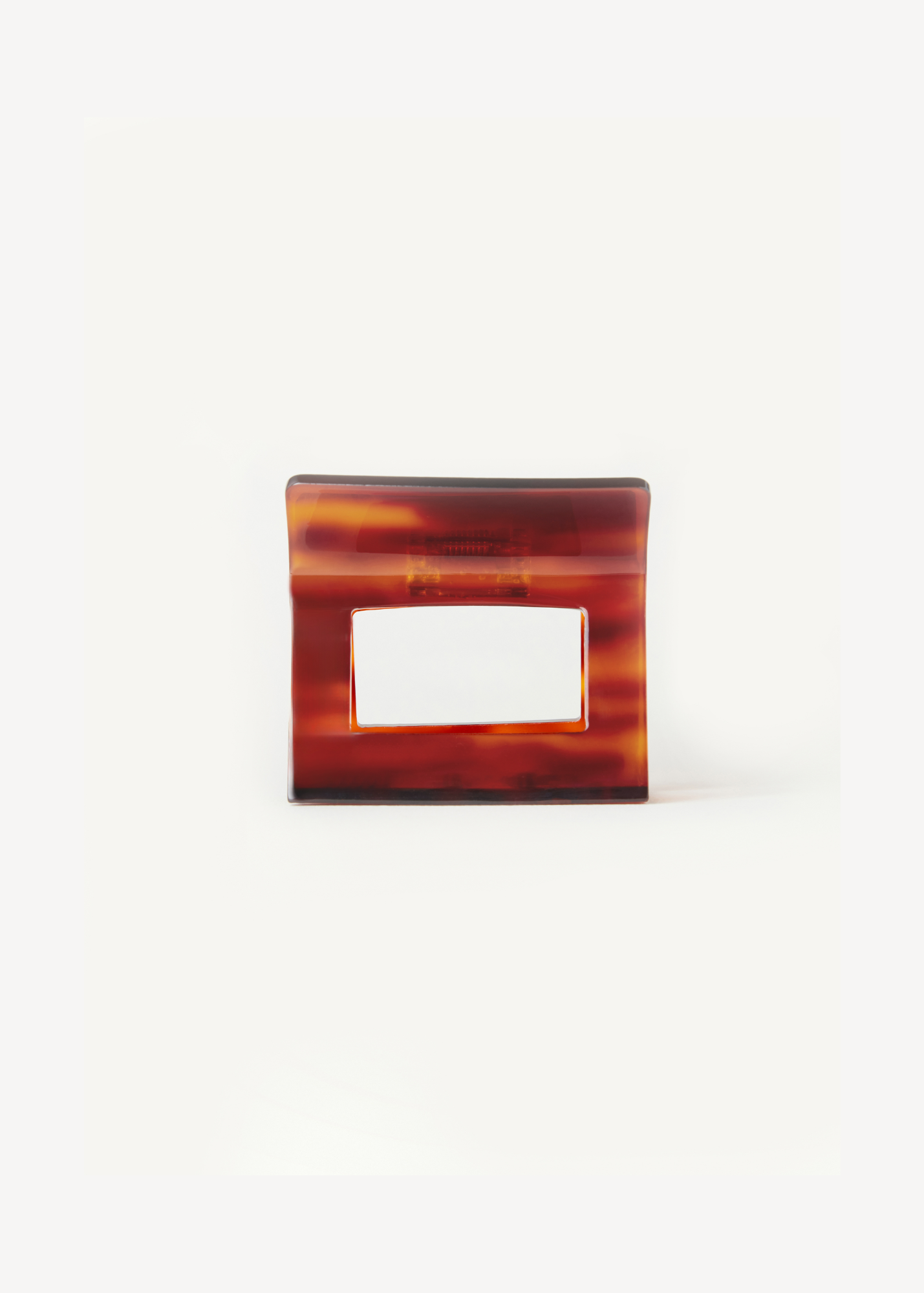Red-toned neutral hair clip on a white background.