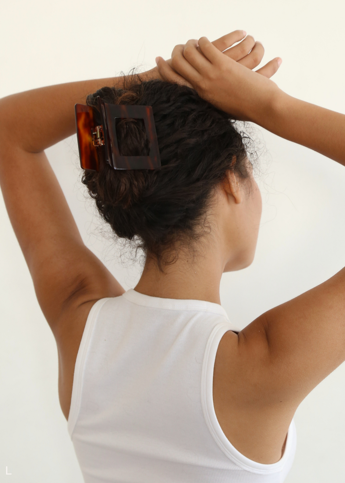 Woman with a red-toned neutral hair clip in her hair against a white background