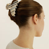 Woman with a medium-sized striped claw clip securing her up-do against a plain background