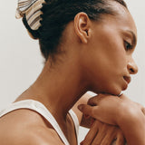 Woman with a striped claw clip looking away from the camera