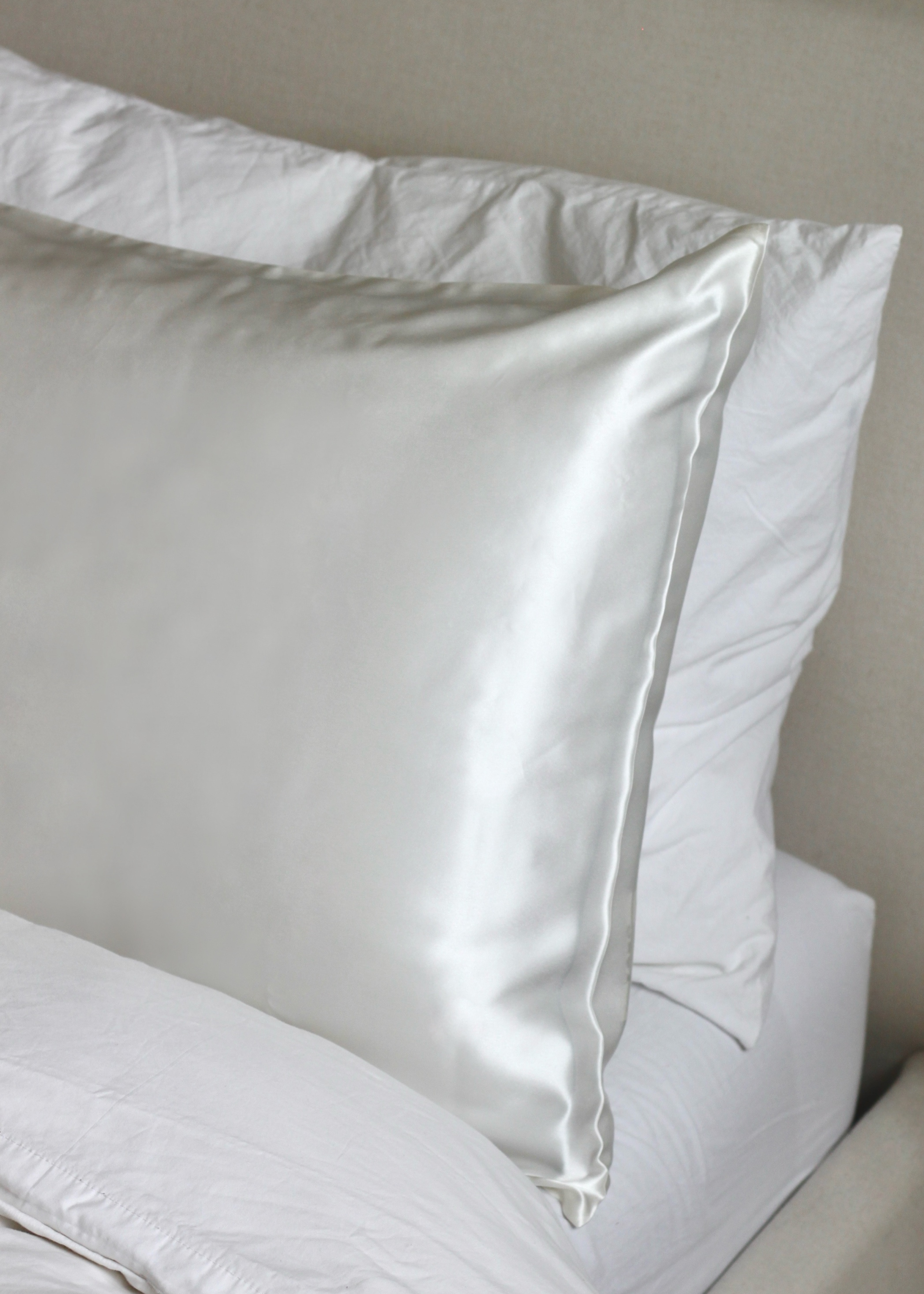 A white silk pillowcase on a pillow, with a smooth and shiny texture.