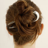 Close-up of a bun with the French pin in silver against a plain background