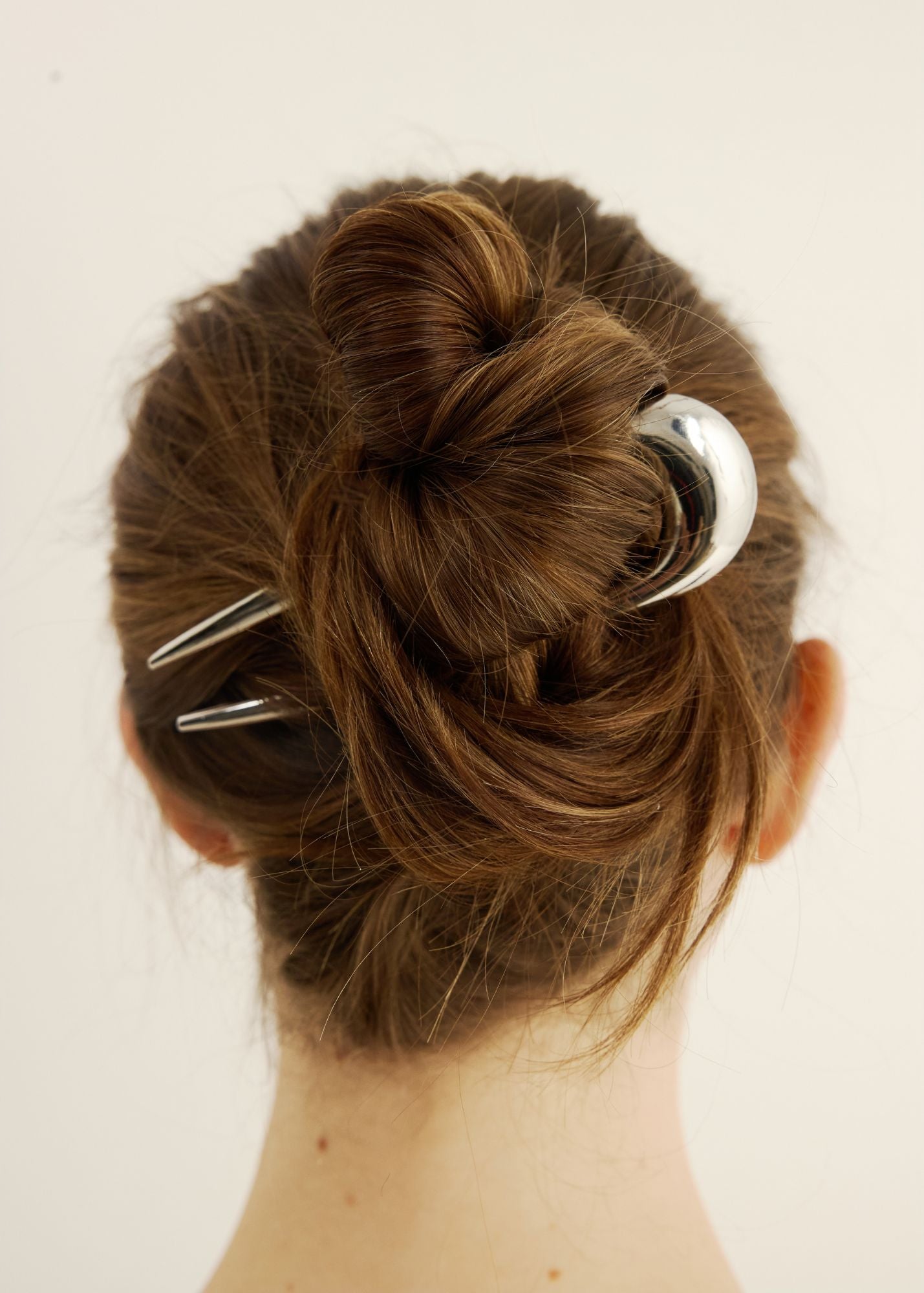 Close-up of a bun with the French pin in silver against a plain background