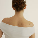 Back view of a woman wearing an off-shoulder white top with a plain background with her hair styled in an updo secured with the French Pin in Silver