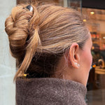 Woman with chestnut coloured hair styled in an updo secured with the French Pin in Silver and wearing a brown coat