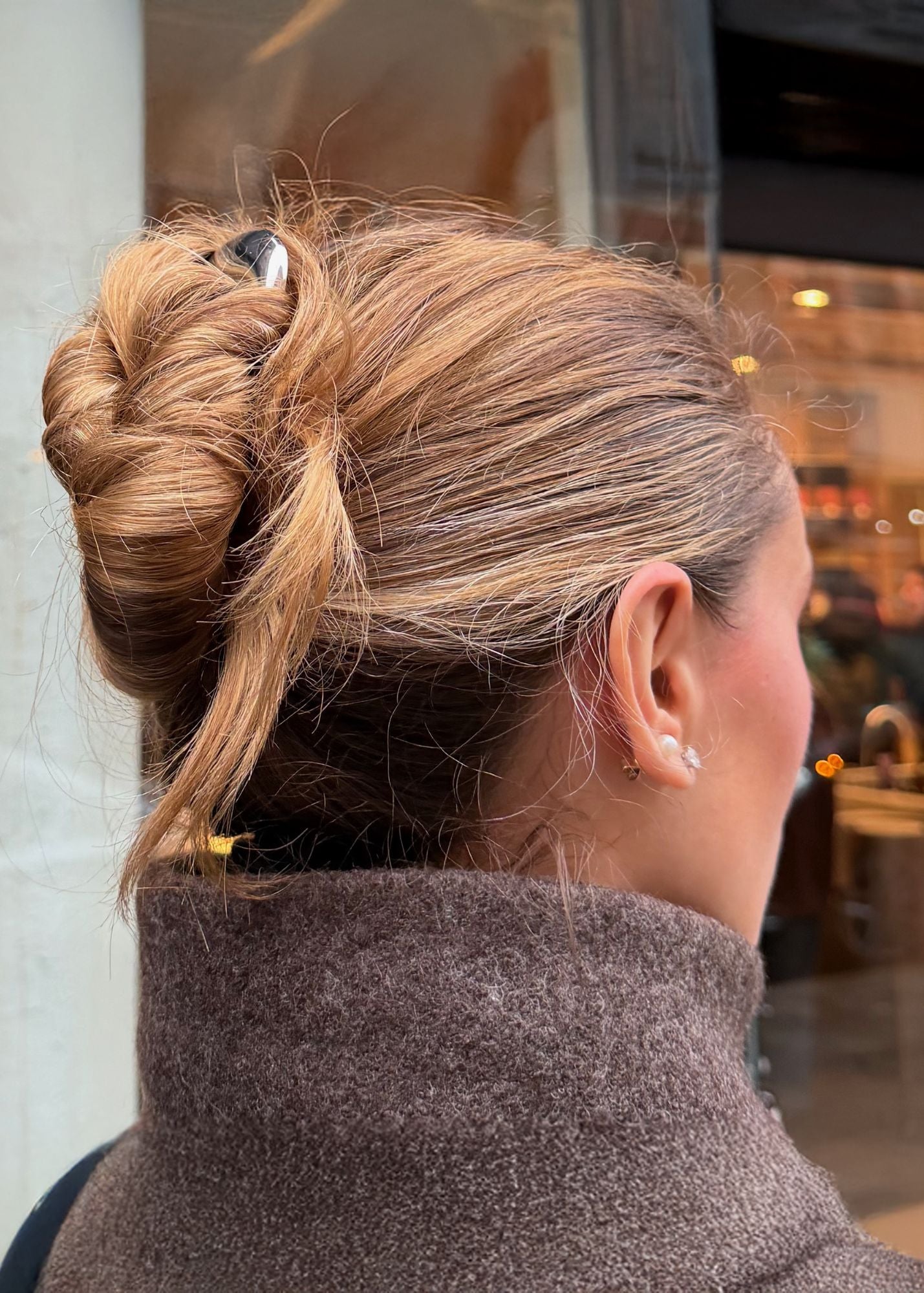 Woman with chestnut coloured hair styled in an updo secured with the French Pin in Silver and wearing a brown coat