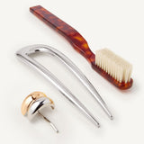 Set of hair accessories including the Detail Brush in Tortoise, French Pin in Silver, and a small mixed metal hair cuff on a white background