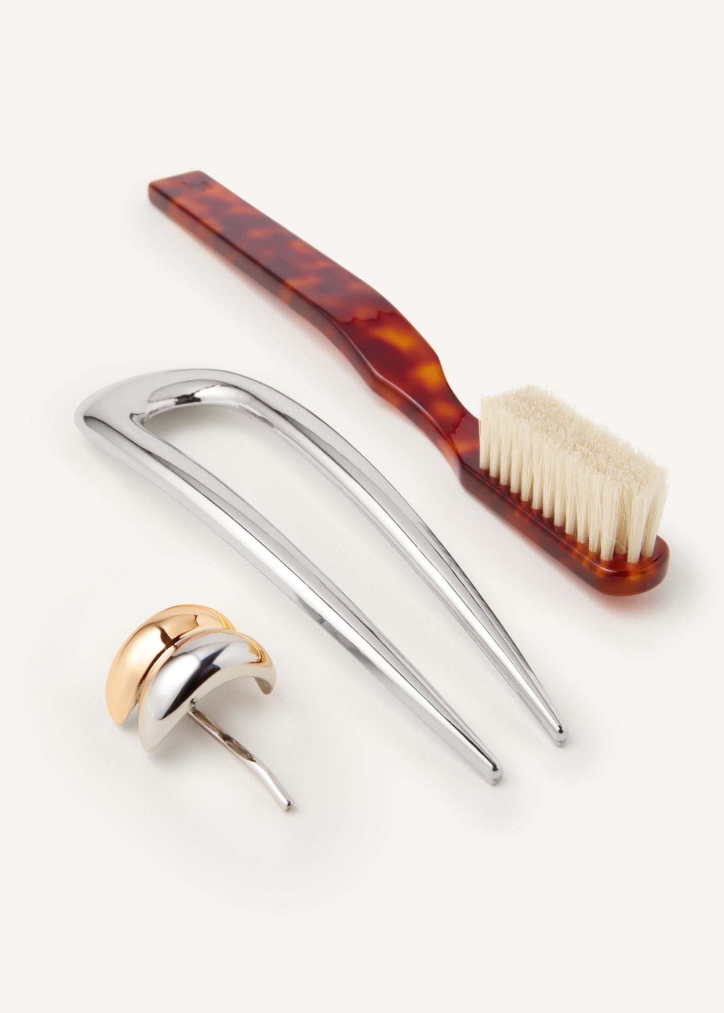 Set of hair accessories including the Detail Brush in Tortoise, French Pin in Silver, and a small mixed metal hair cuff on a white background
