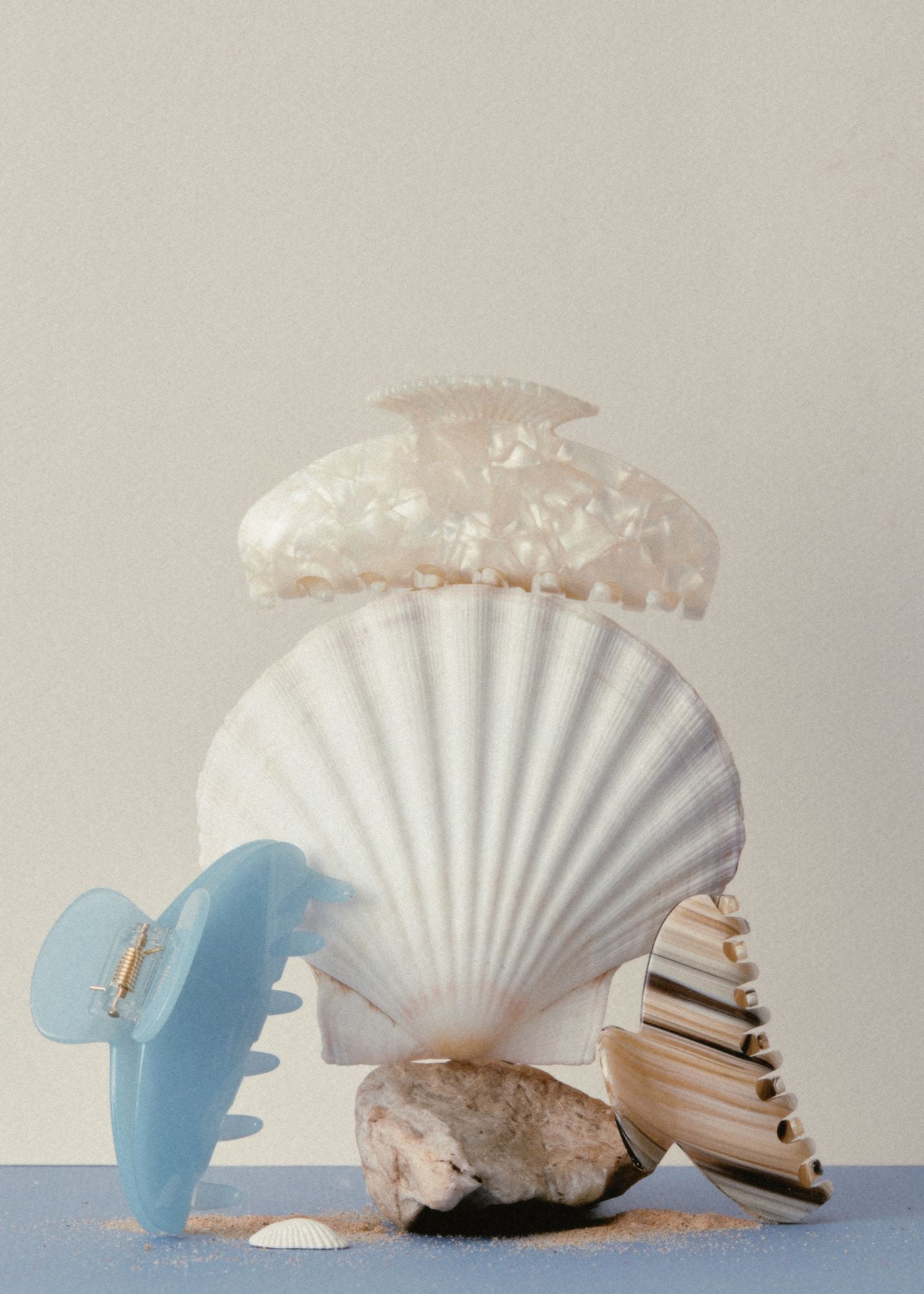3 hair claw clips resting on a seashell against a beige background 