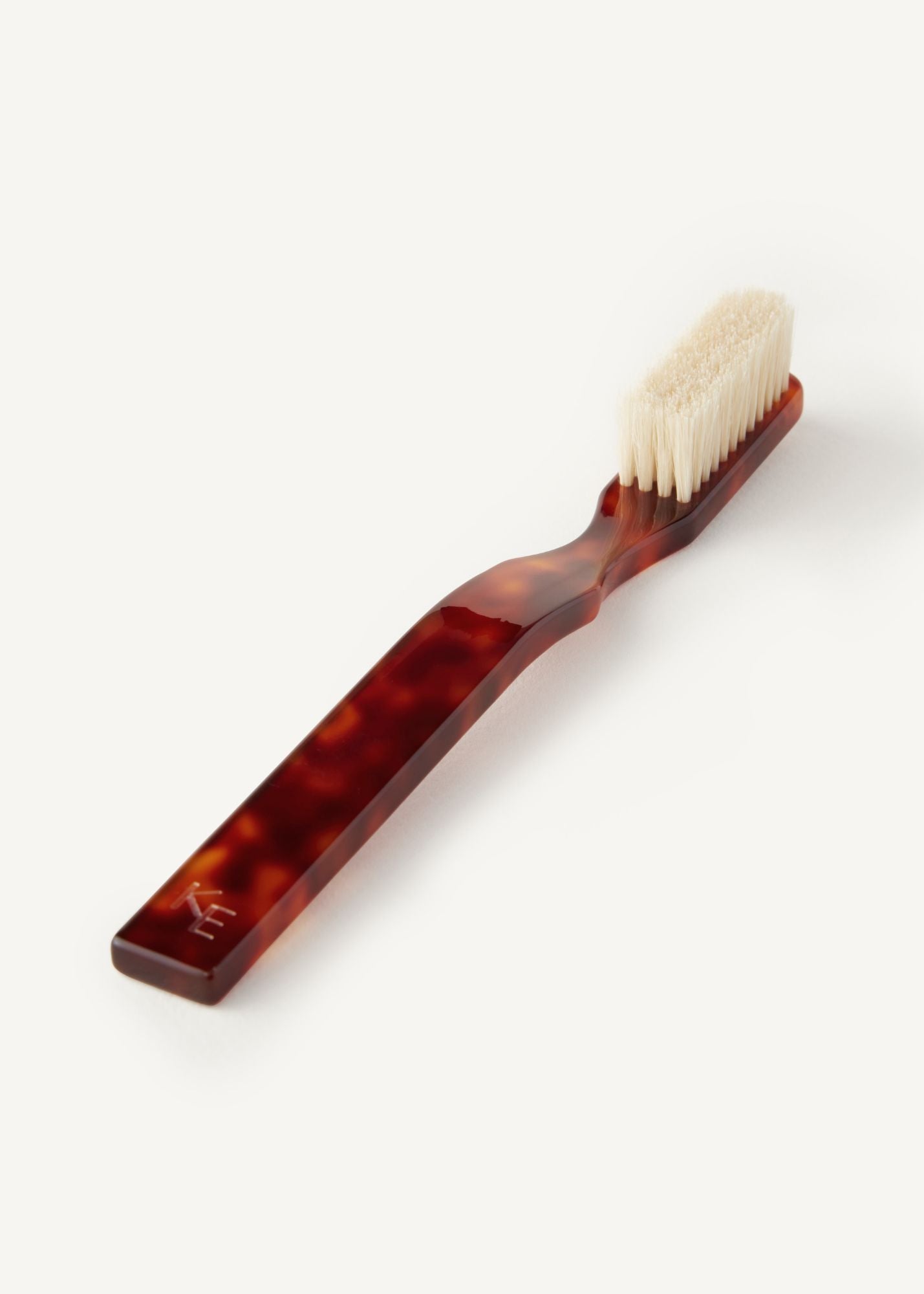 The Detail Brush in Tortoise, a boar bristle brush laying flat on a white background