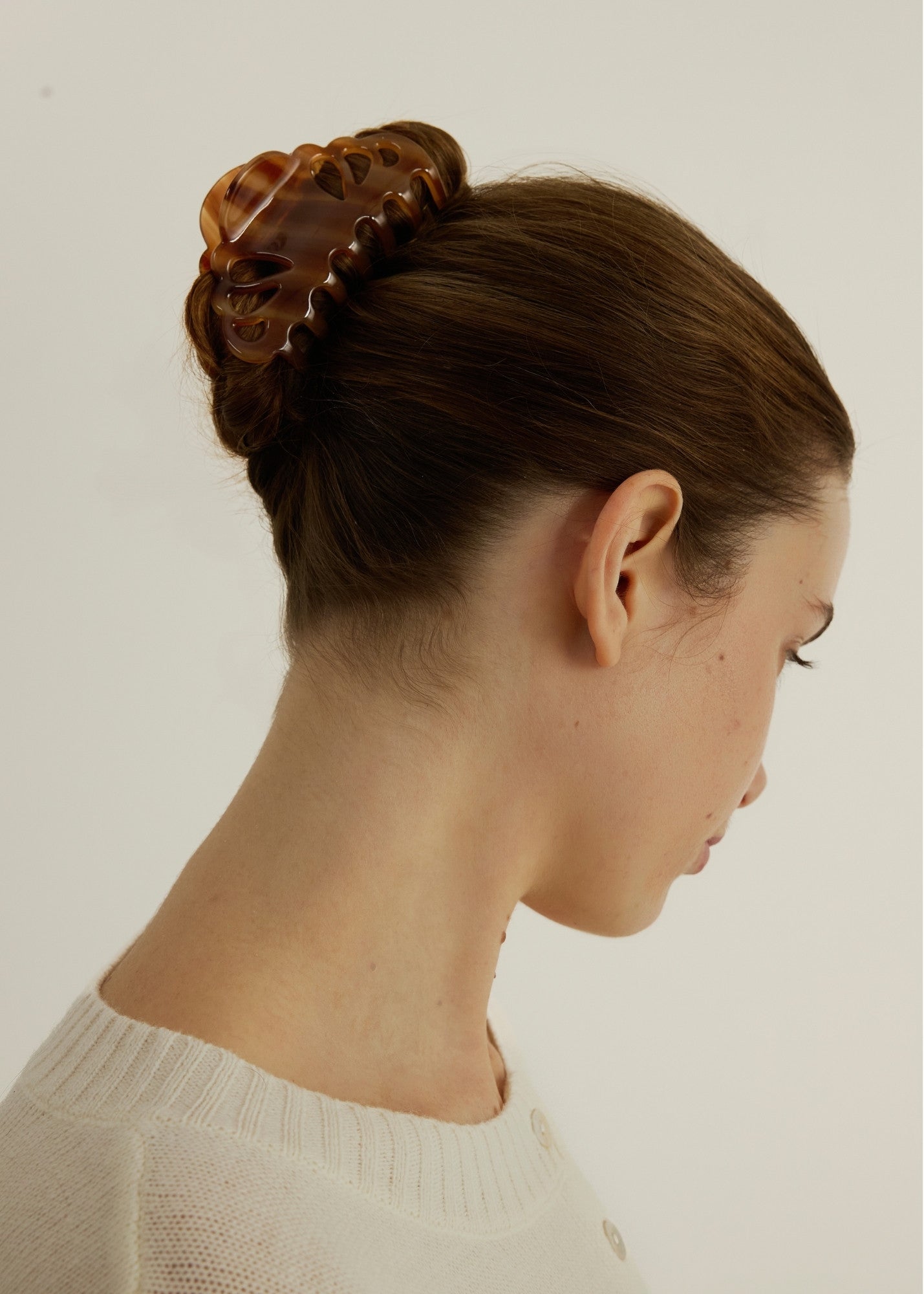 Woman with styled hair using the large Icon Clip in Honey to secure her up-do against a neutral background