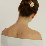 Woman with dark brown hair styled in a bun secured with the Sculpt Clip in Oak, wearing a white tank top against a white background