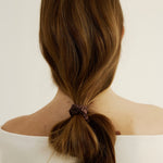 Woman with brown hair styled in a unique ponytail secured with the silk hair tie in espresso