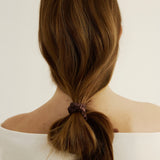 Woman with brown hair styled in a unique ponytail secured with the silk hair tie in espresso