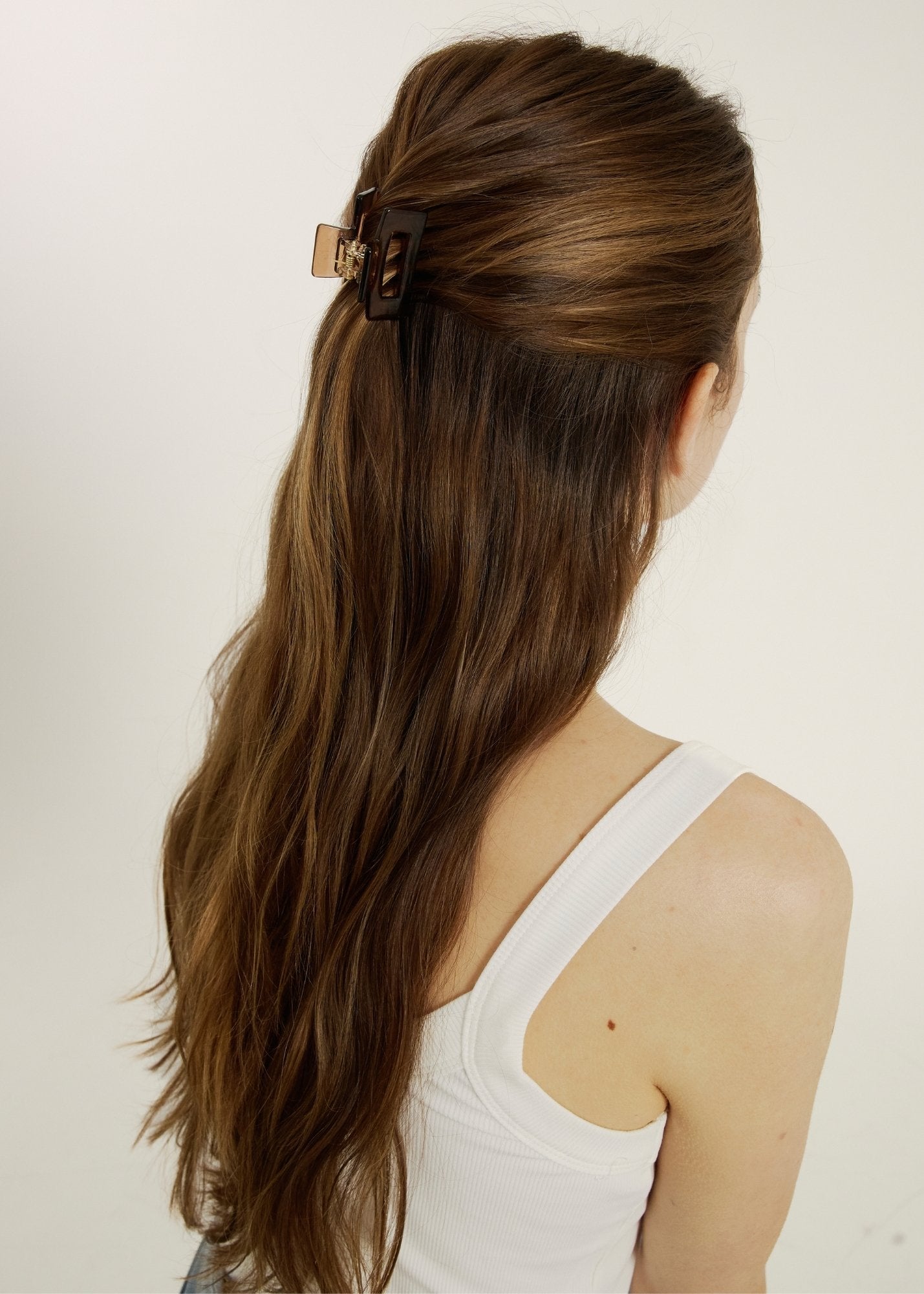 Woman with long dark hair styled half-up, half-down secured with a mini daily clip in cider against a neutral background
