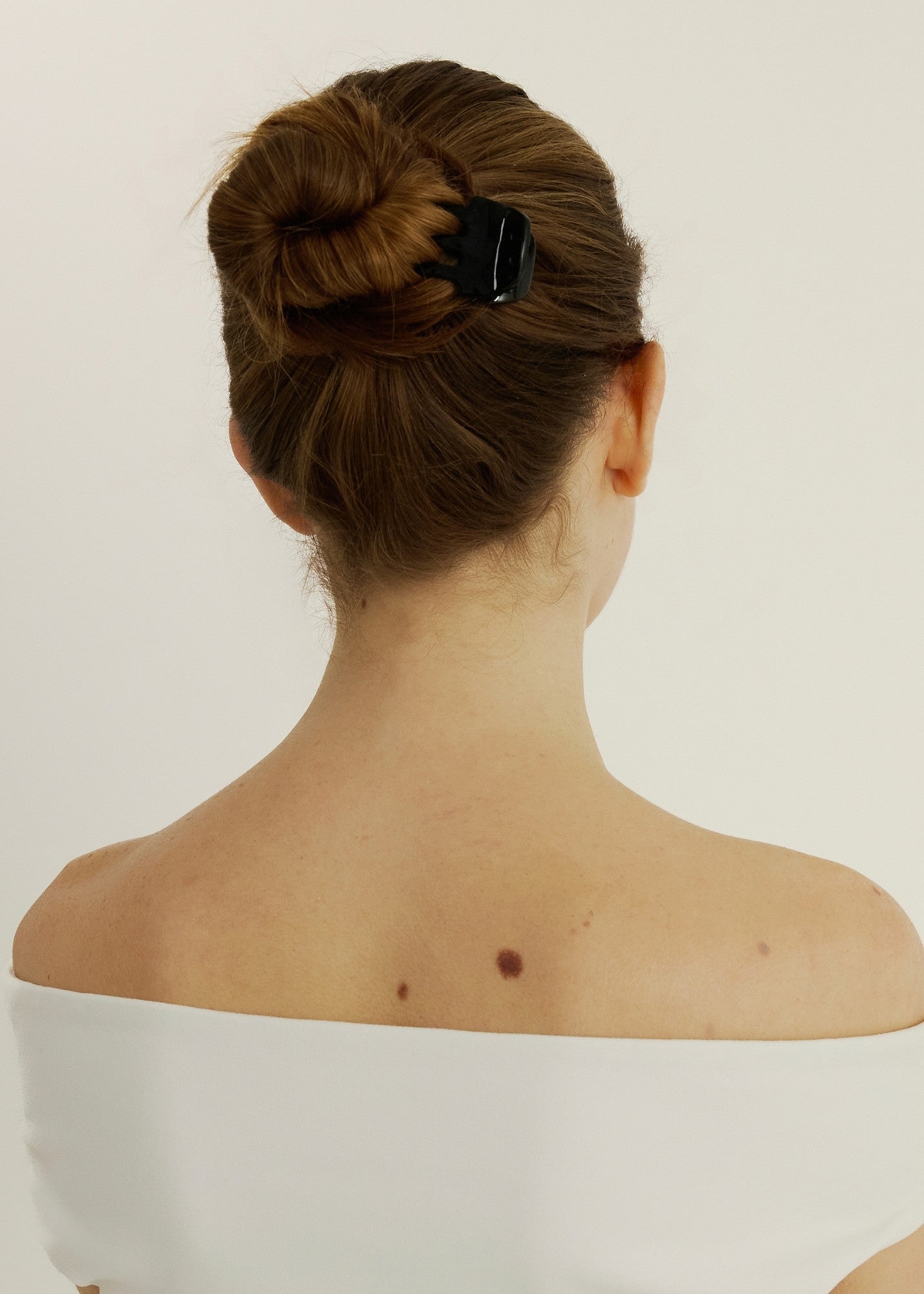 Girl with brown hair in a bun secured with sculpt clip
