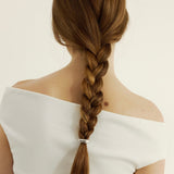 Woman with braided hair with a hair cuff
wearing a white off-shoulder top on a plain background