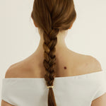 Person with a braided hairstyle with a hair cuff on a plain background