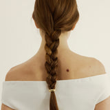 Person with a braided hairstyle with a hair cuff on a plain background