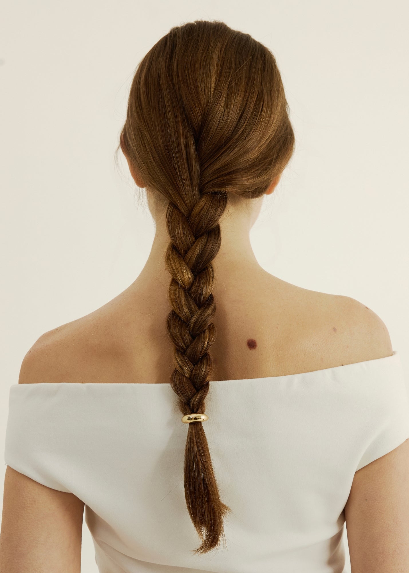 Person with a braided hairstyle with a hair cuff on a plain background