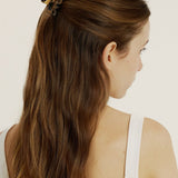Close up of woman with dark brown hair in a half up, half down hairstyle secured with a mini light tortoise coloured hair claw clip.