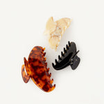 Three Demi hair clips in the colours tortoise, beige, and black on a white background