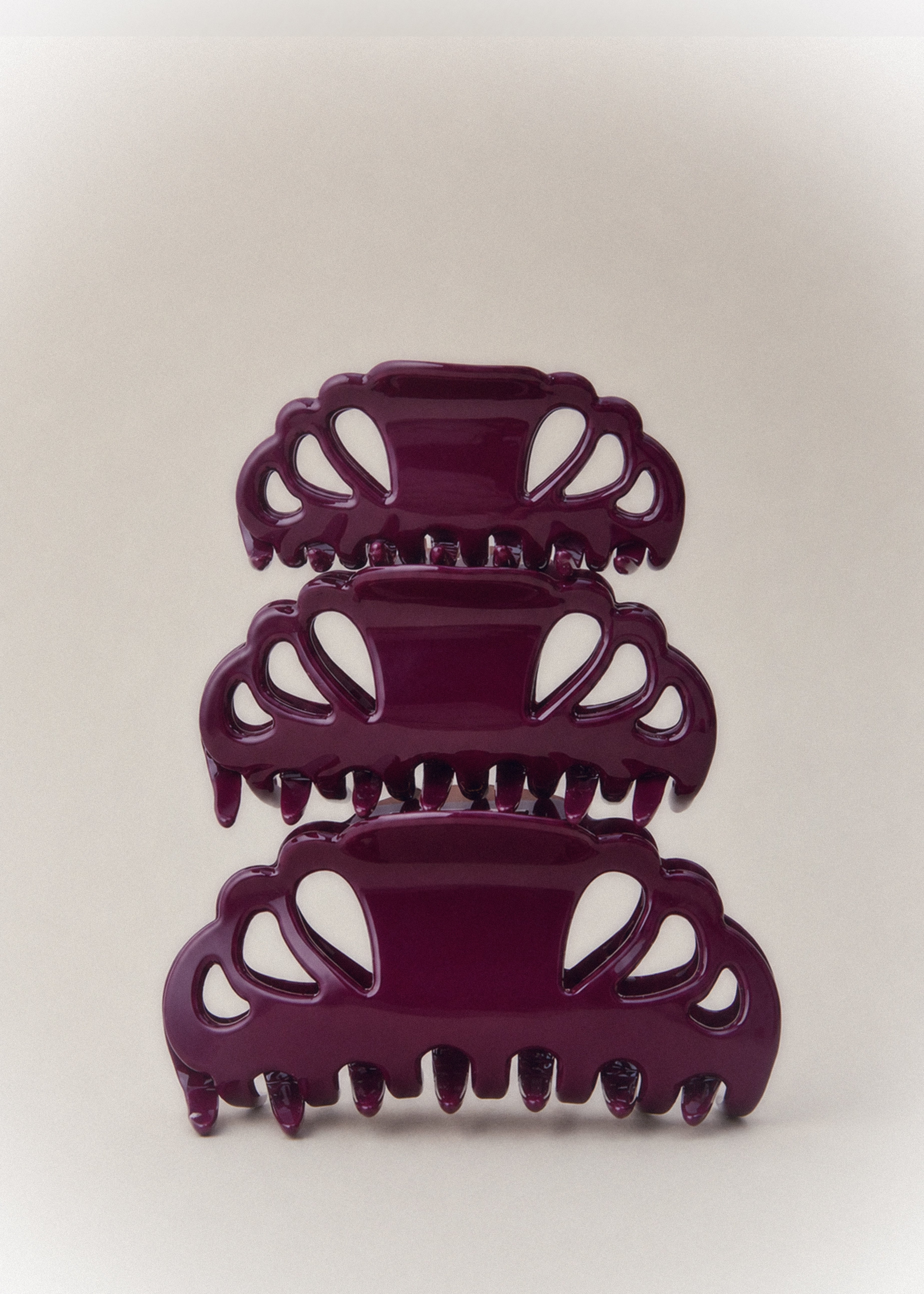 Three glossy dark purple claw hair clips stacked vertically on a light gray background.