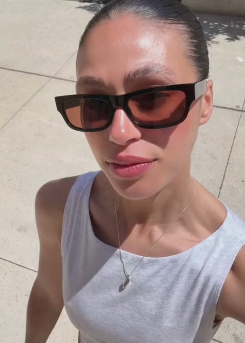 Woman outside on a sunny day wearing the Haven sunglasses in black with a brown lens 