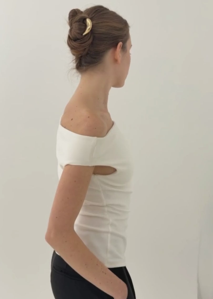 Woman with brunette hair styled in an up do secured with the French Pin in Gold wearing a white, off the shoulder top against a white background